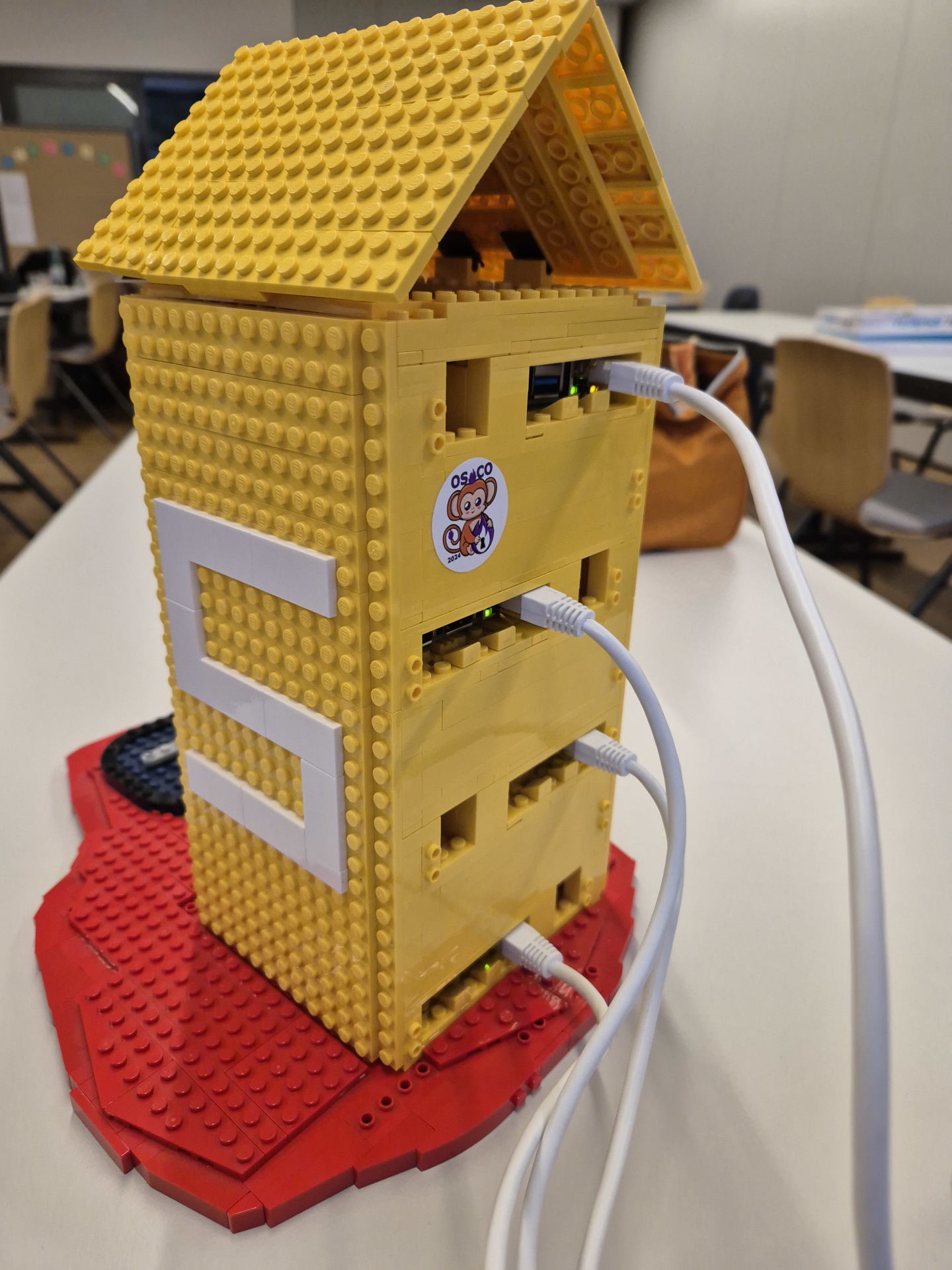 Multijuicer Cluster The picture shows a cluster made of multiple Raspberry Pies. The enclosure is the juice package from the logo of the OWASP juice shop and is made out of lego bricks. Someone put a osco 2024 sticker on it.
