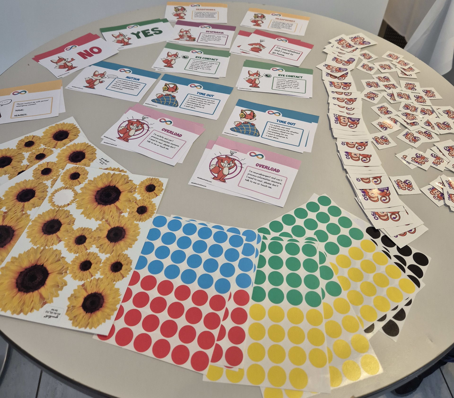 Tell us if you want A table with supportive stuff to tell others your needs. Sunflower stickers to show invisible disability. Colored stickers to show if you want to be on photos or not. Cards to show mental overload or that you need a timeout. And some osco 2024 stickers.