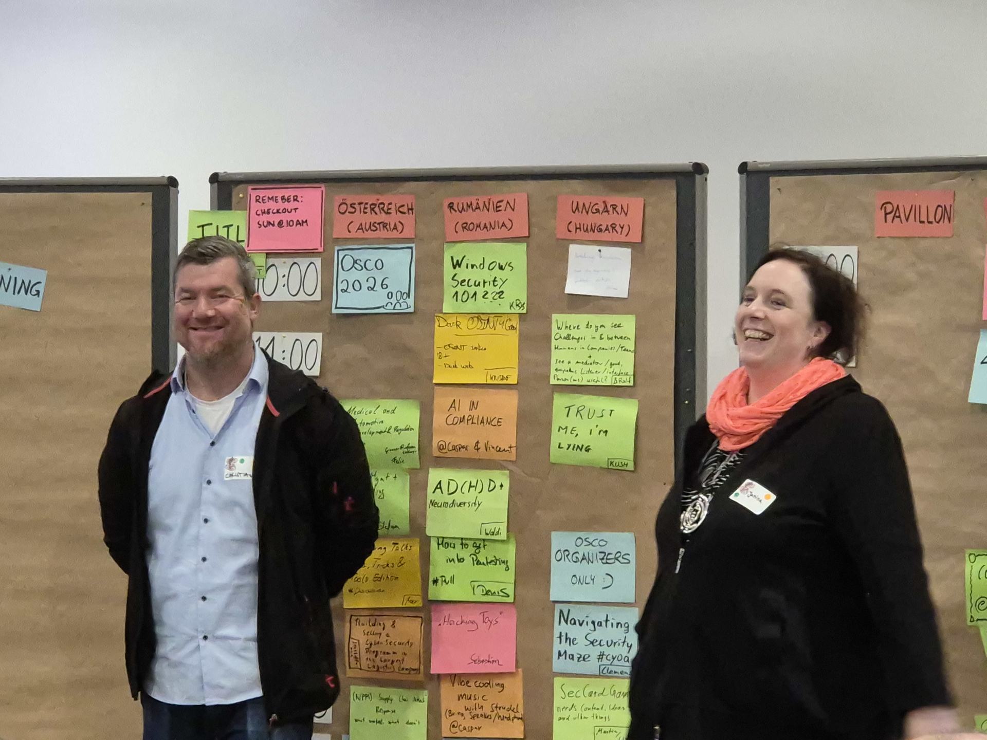 The picture shows two of our organizers in front of the planning board. They are laughing.